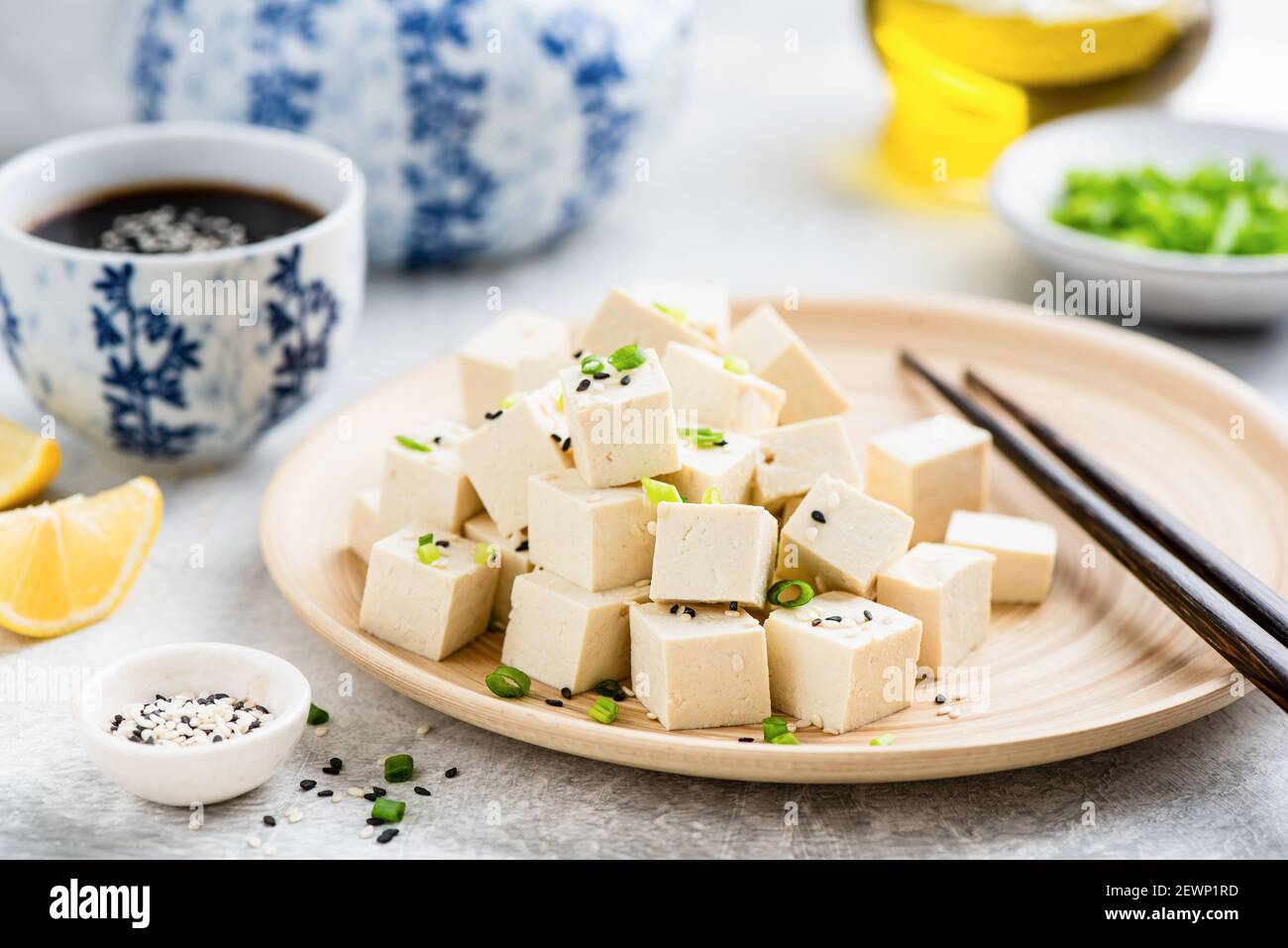Cubetti di tofu su piatto di bambù con bastoncini e salsa di soia. Supplemento di carne vegana Foto Stock