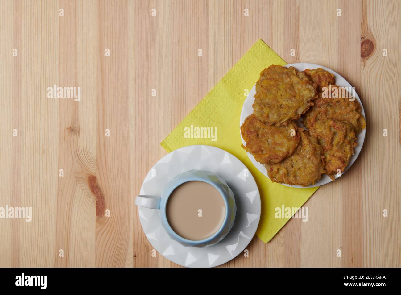 frittelle di patate in un piatto e una tazza di caffè su sfondo di legno Foto Stock