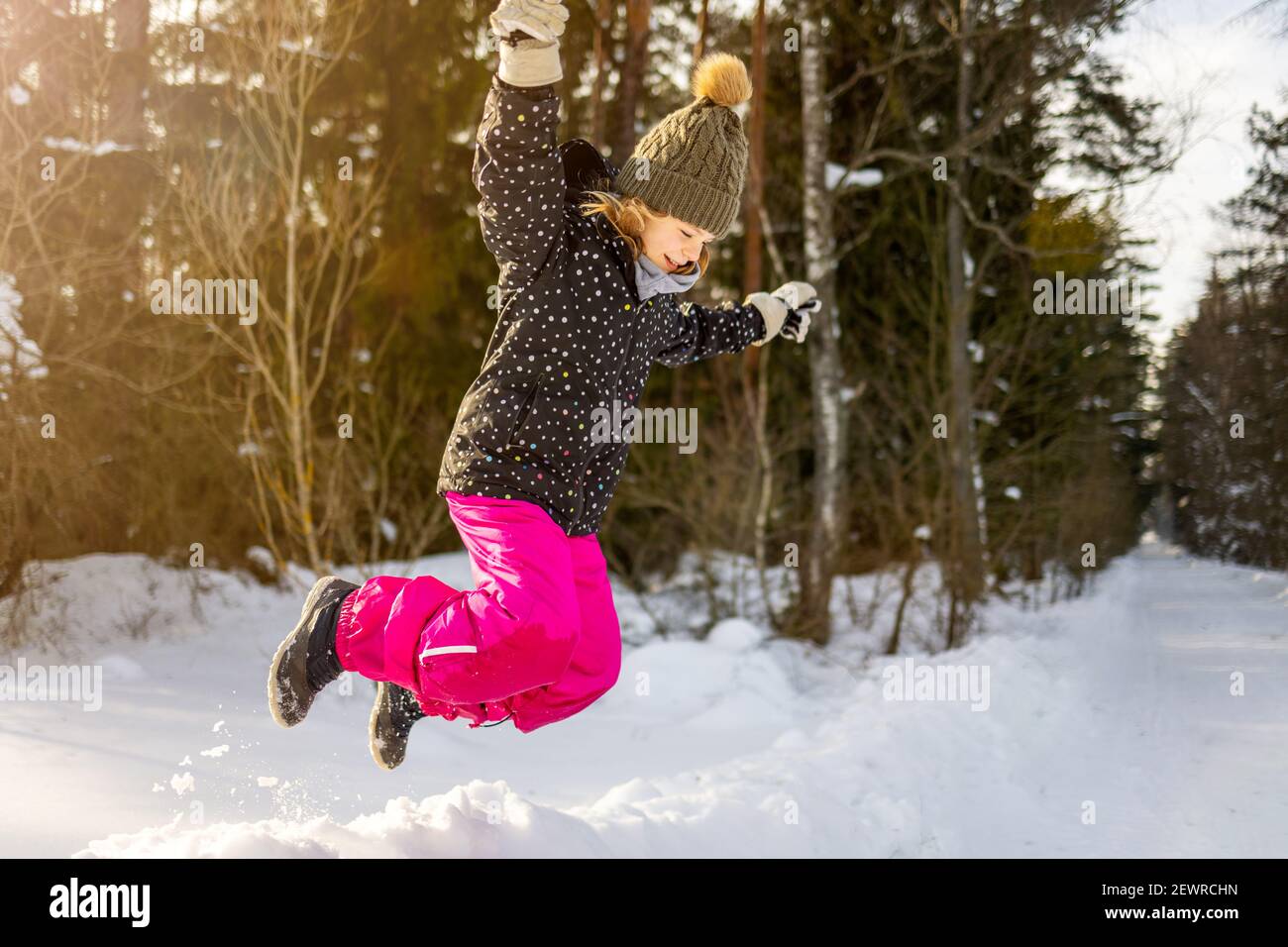 Ragazza che salta nella foresta in giornata innevata Foto Stock