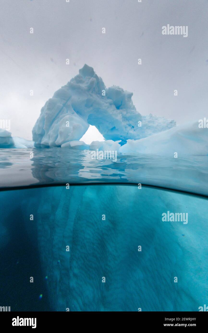 Vista sopra e sotto di un arco formato in un iceberg a Cuverville Island, canale di Ererra, Antartide, regioni polari Foto Stock