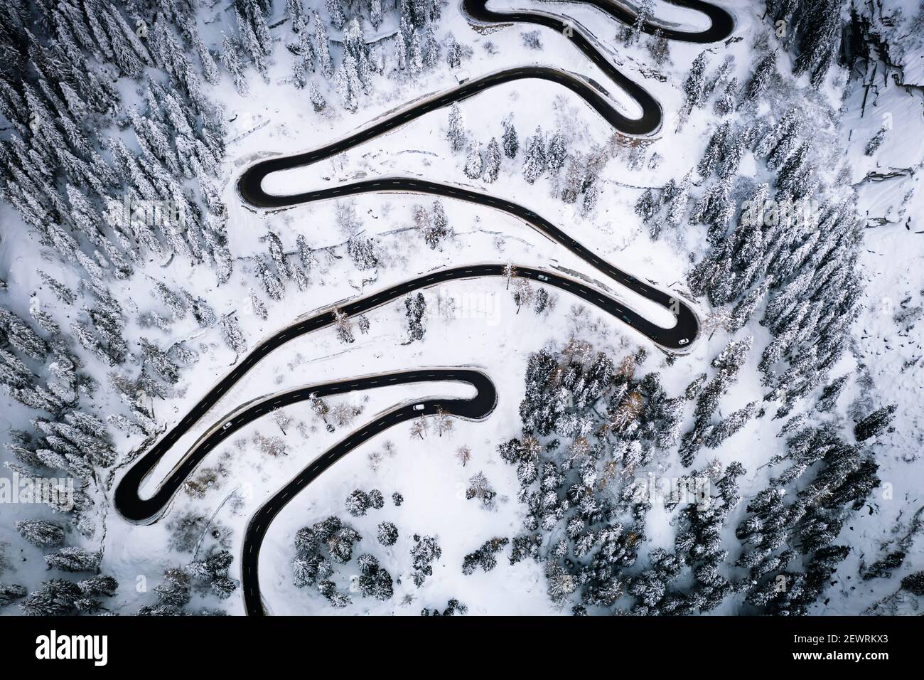 Vista aerea di auto su strette curve di strada di montagna che attraversa la foresta innevata, Svizzera, Europa Foto Stock