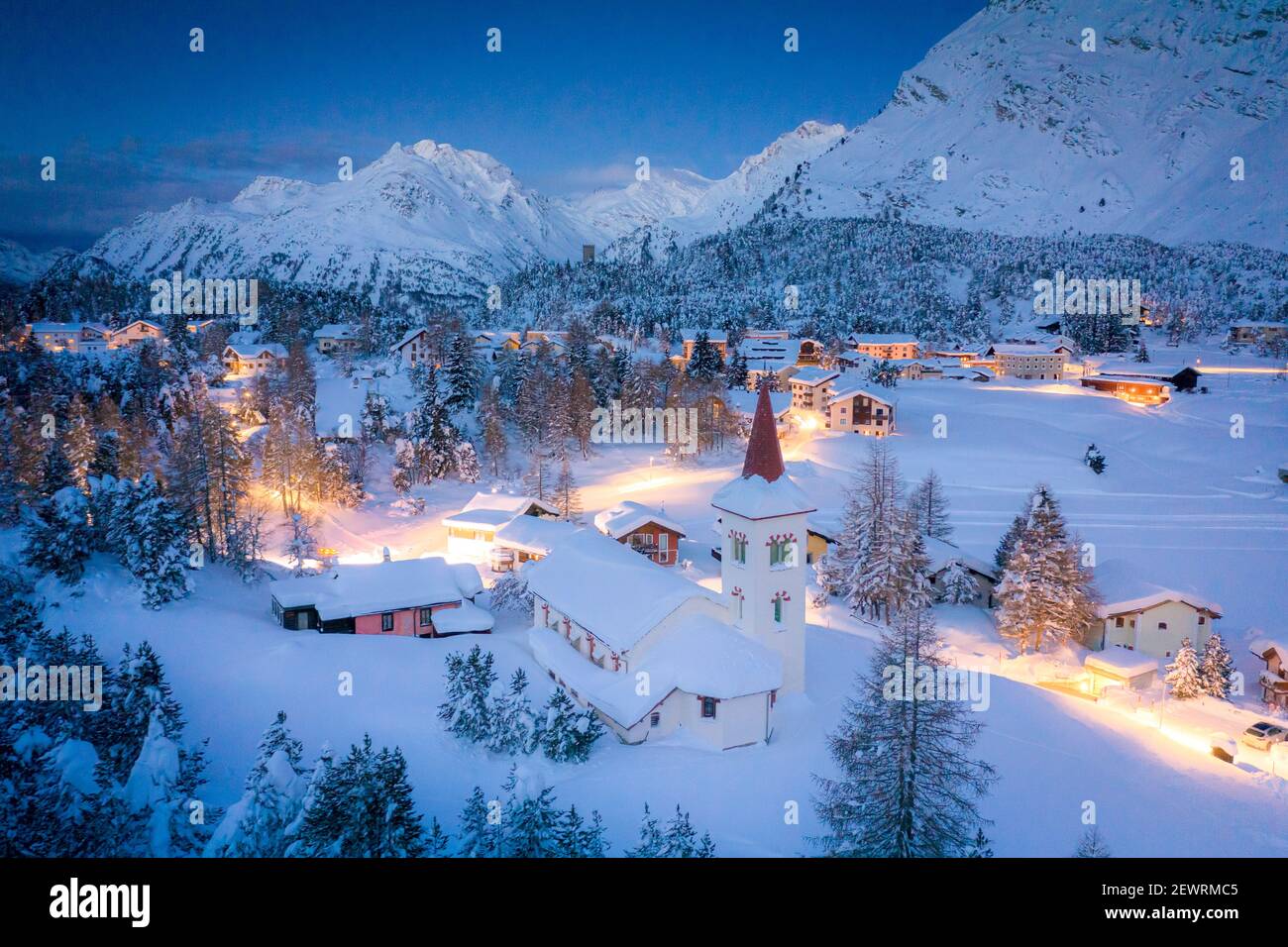 Crepuscolo su Chiesa Bianca e Maloja villaggio coperto di neve, Bregaglia, Engadina, Grubunden Canton, Svizzera, Europa Foto Stock