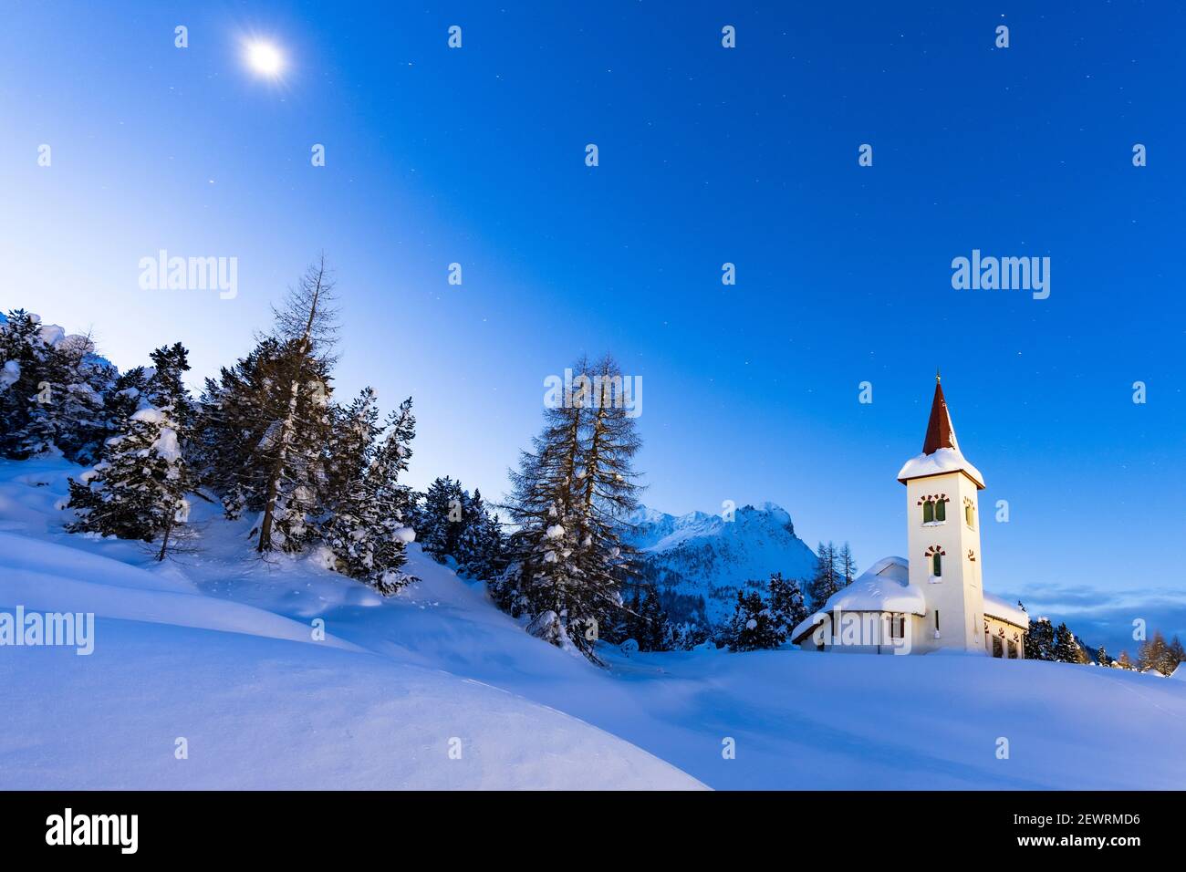 Crepuscolo su Chiesa Bianca nel paesaggio innevato illuminato dalla luna, Maloja, Valle di Bregaglia, Engadina, Cantone di Graubunden, Svizzera, Europa Foto Stock