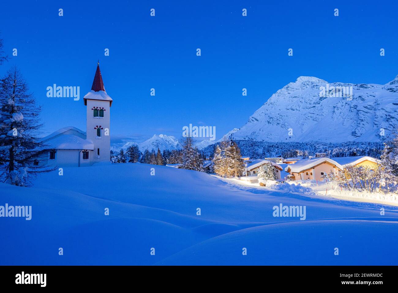 Villaggio alpino di Maloja e Chiesa Bianca coperto di neve al crepuscolo, Bregaglia, Engadina, Cantone Graubunden, Svizzera, Europa Foto Stock