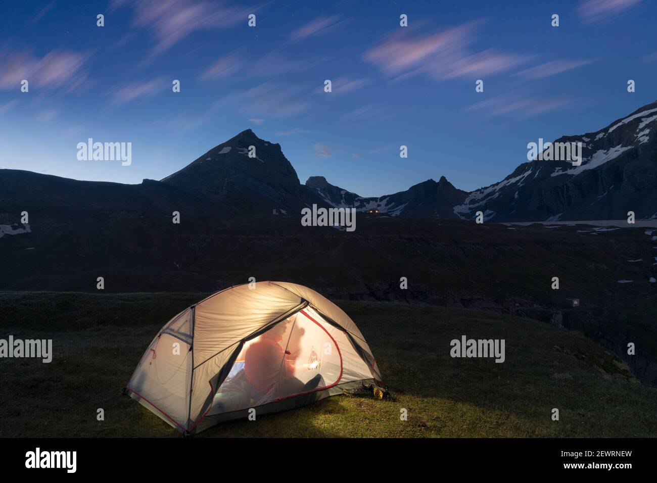 Silhouette di escursionista all'interno della tenda illuminata sopra il lago Limmernsee al tramonto, Canton Glarona, Svizzera, Europa Foto Stock