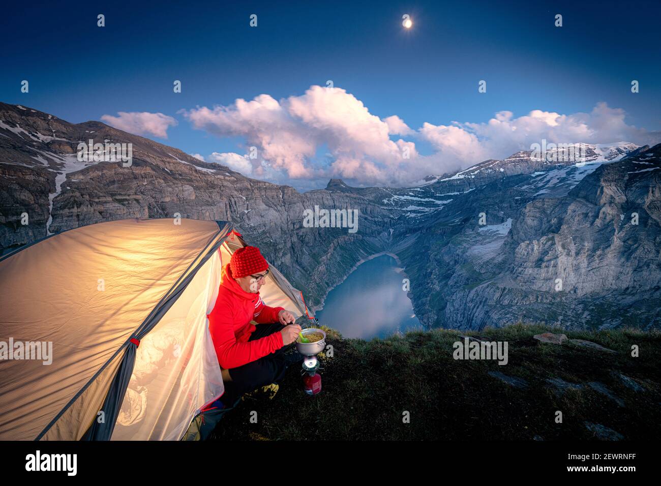 Uomo escursionista con tenda con stufa da campeggio sul crinale sopra il lago Limmernsee, Canton Glarona, Svizzera, Europa Foto Stock