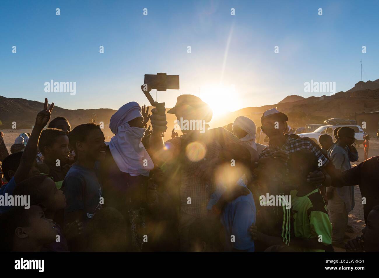 Retroilluminazione di una folla di bambini e uomini Tuareg, Oasi di Timia, Air Mountains, Niger, Africa Foto Stock