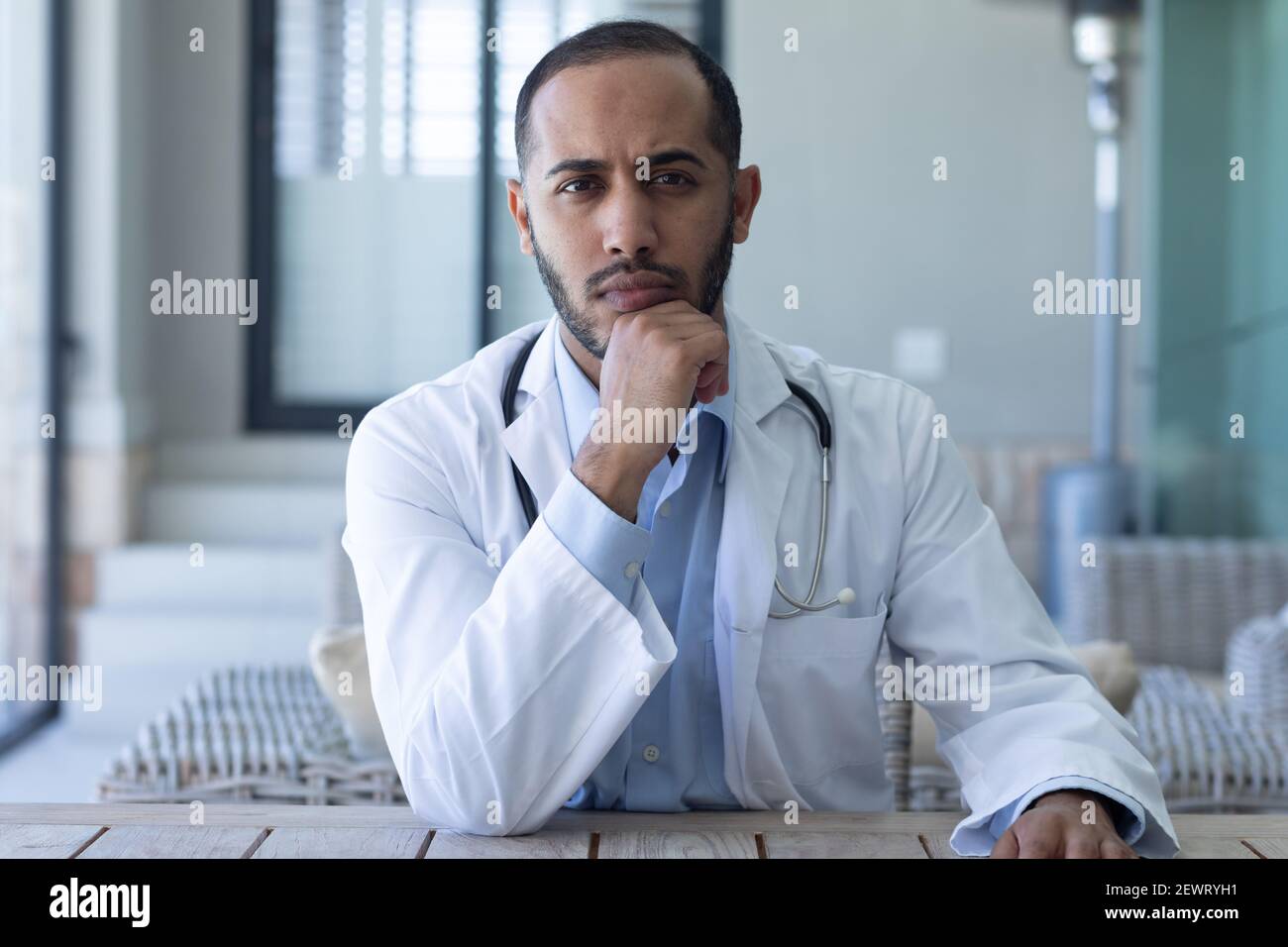 Ritratto del medico maschio caucasico guardando la macchina fotografica e. strofinando il mento Foto Stock