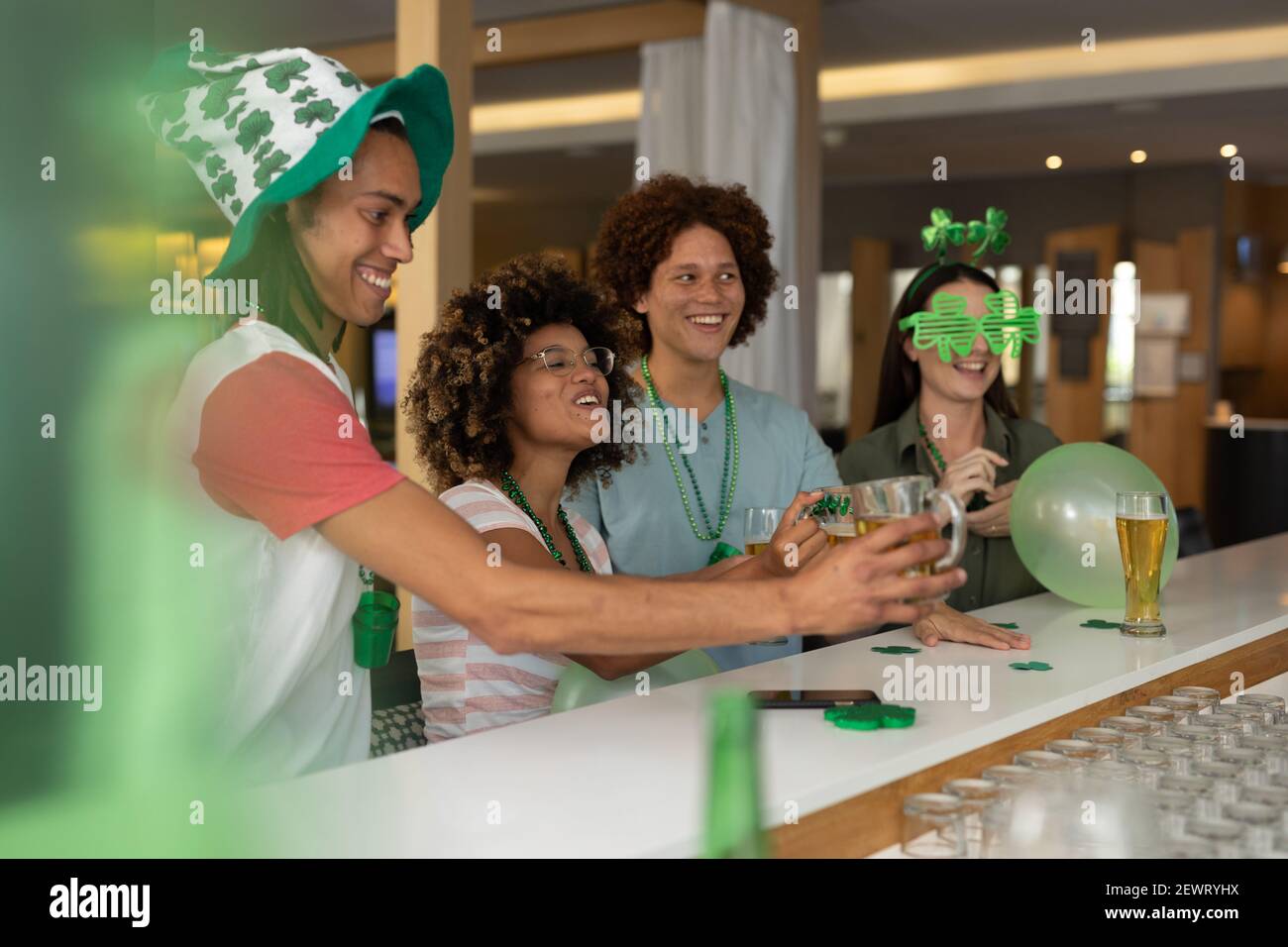 Un gruppo eterogeneo di amici felici che festeggiano la giornata di san patrizio un bar Foto Stock
