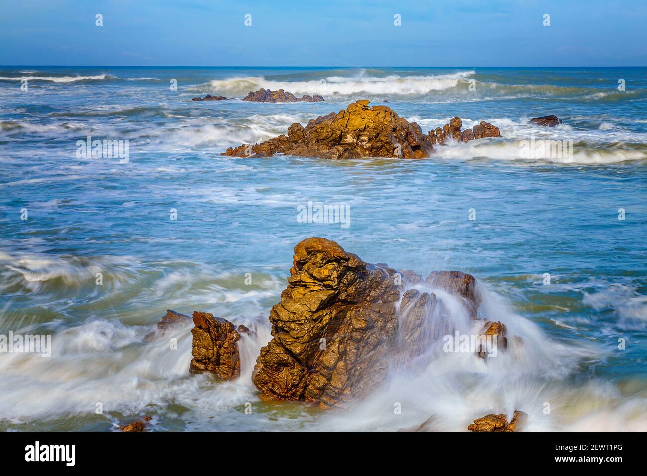 Vista panoramica della costa di Aghulas, il punto più meridionale dell'Africa. Onde che lavano sopra le rocce in una zona dove le tempeste enormi prevalgono solitamente considerate da sai Foto Stock