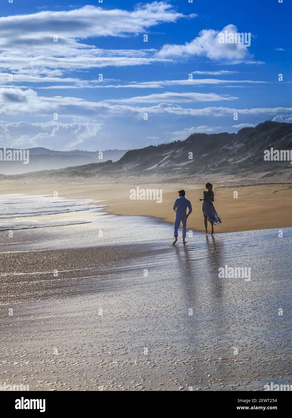 Una coppia che cammina sulla spiaggia a bassa marea Foto Stock