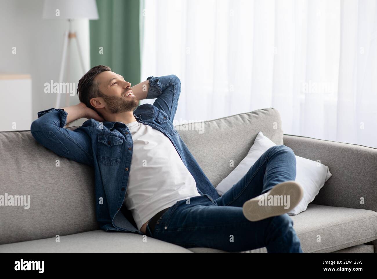 Uomo di mezza età rilassato che riposa sul divano a casa Foto Stock