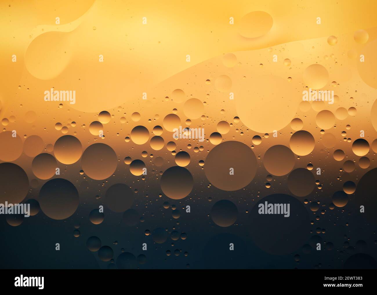 Un primo piano di gocce d'olio sull'acqua illuminate con luce colorata Foto Stock