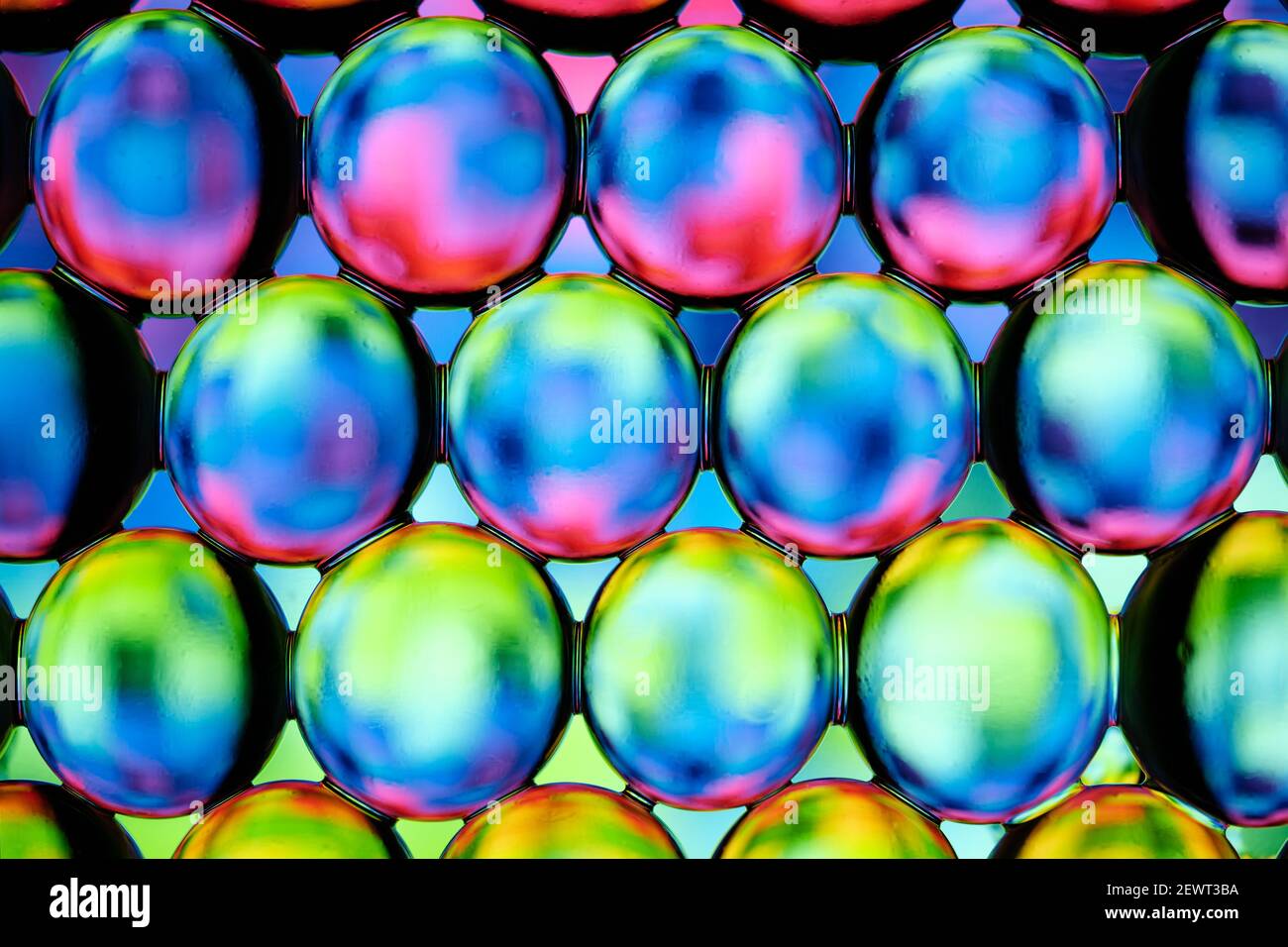 Una vista macro di una fila di orbe d'acqua limpida, o orbeez, che riflettono i colori Foto Stock