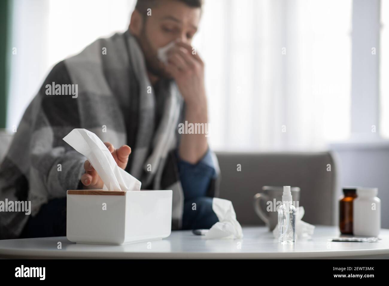 Uomo malato starnutire il naso, prendendo tovaglioli, casa interiore Foto Stock