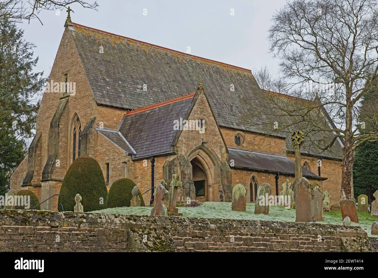 St Helen's e All Saints, antico villaggio di campagna inglese con cimitero e muro di pietra a secco nella comunità rurale Foto Stock