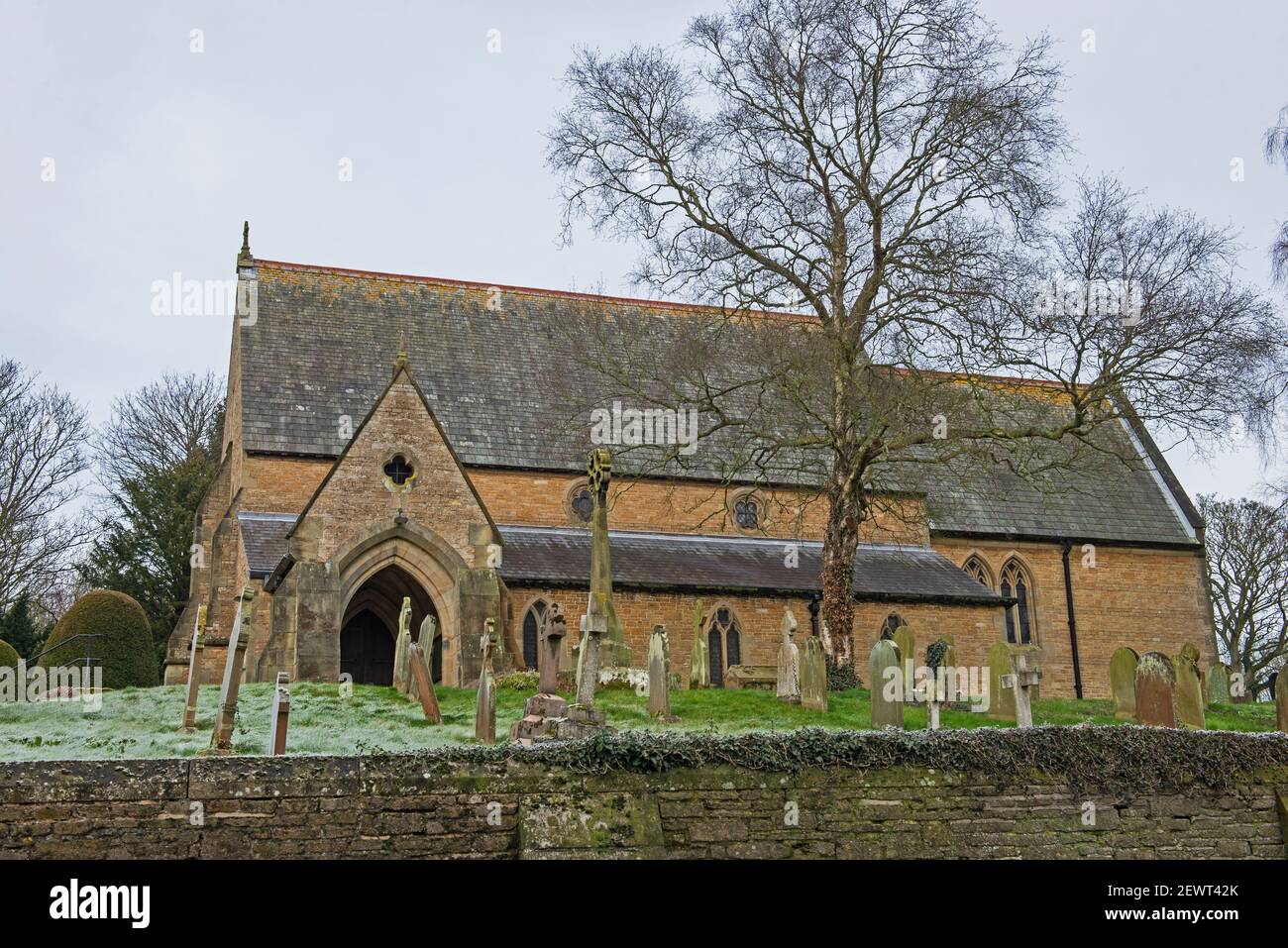 St Helen's e All Saints, antico villaggio di campagna inglese con cimitero e muro di pietra a secco nella comunità rurale Foto Stock