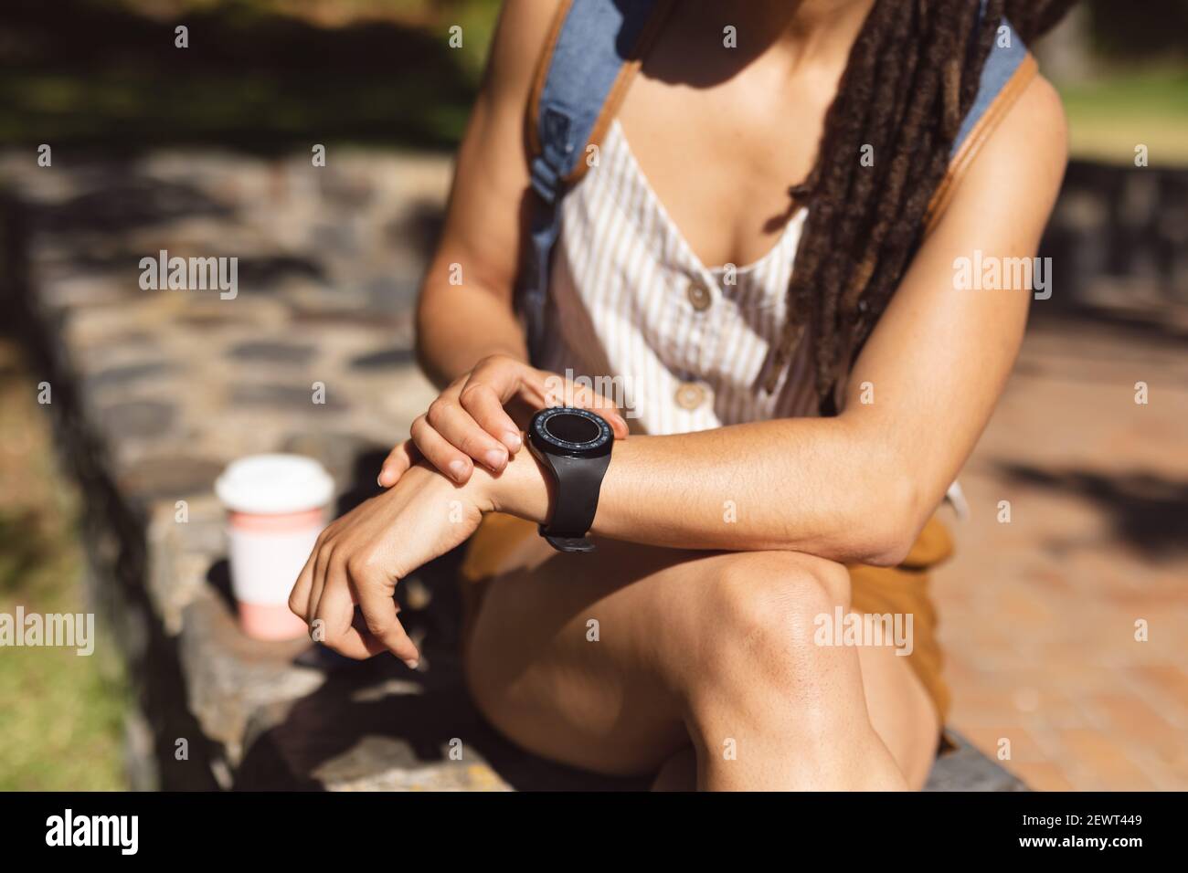 Sezione centrale della donna afroamericana seduto con il suo smartwatch dentro parcheggio Foto Stock