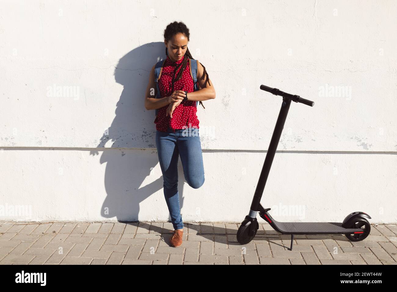 Donna afroamericana accigliata, controllando il tempo sullo scooter smartwatch accanto a lei Foto Stock
