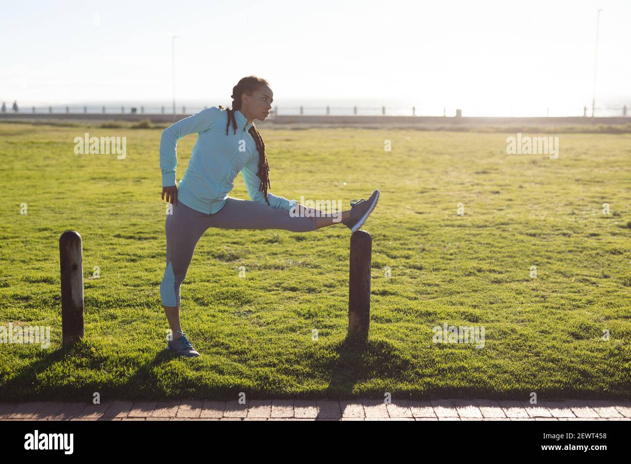 Donna afroamericana che si concentra, indossando abiti sportivi che si esercitano in un parco stretching Foto Stock