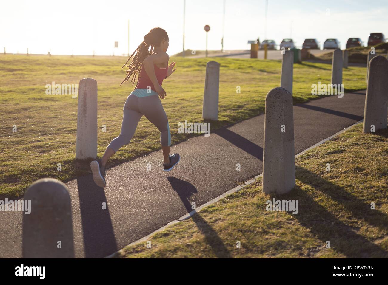 Donna afroamericana che si esercita nel parco, correndo sul sentiero nella giornata di sole Foto Stock