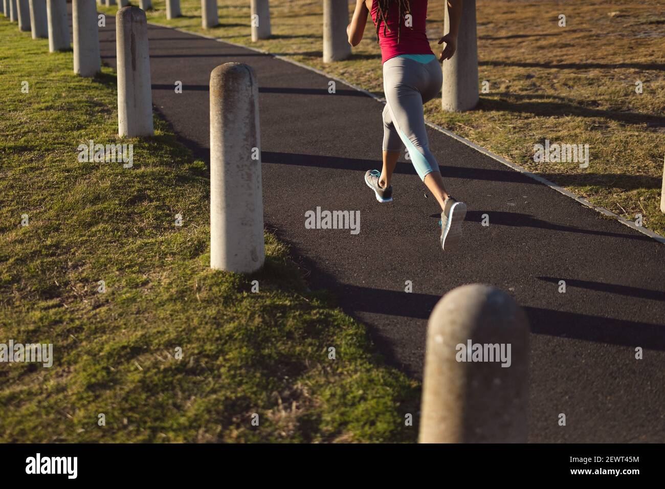 Sezione bassa della donna afroamericana che indossa abiti sportivi che si esercitano nel parco jogging sul sentiero Foto Stock