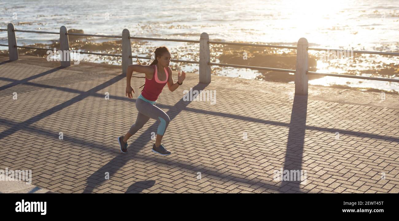 Donna afroamericana che si concentra sull'esercizio su una passeggiata dal corsa in mare Foto Stock