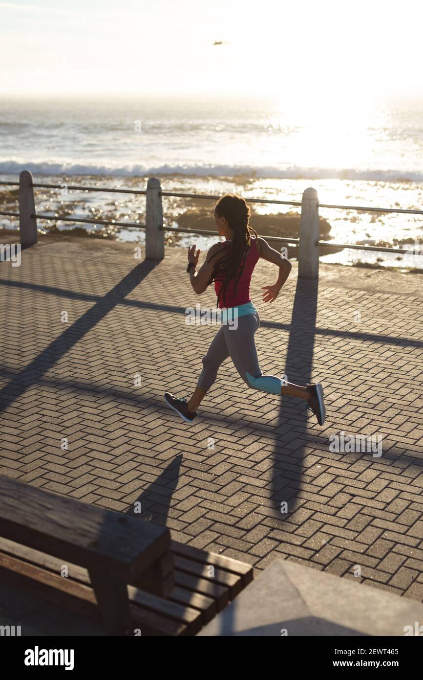 Donna afroamericana che si esercita su una passeggiata sul mare in esecuzione Foto Stock