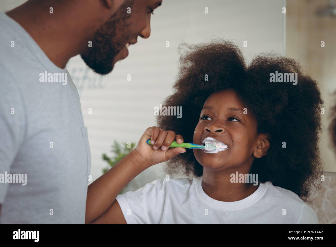 Ragazza afroamericana e suo padre spazzolando i denti insieme Foto Stock
