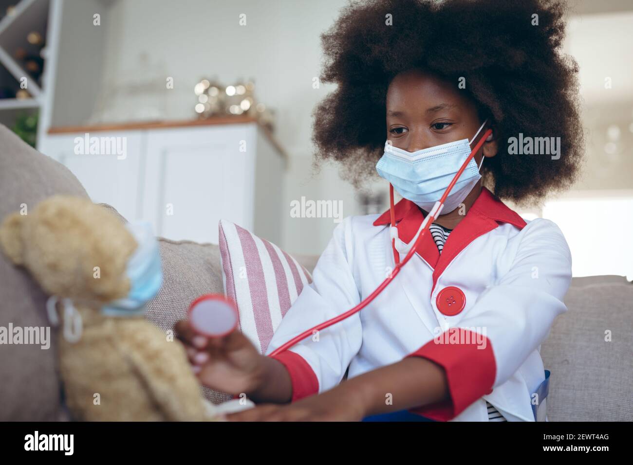Ragazza afroamericana che gioca medico e paziente con il suo teddy orso Foto Stock