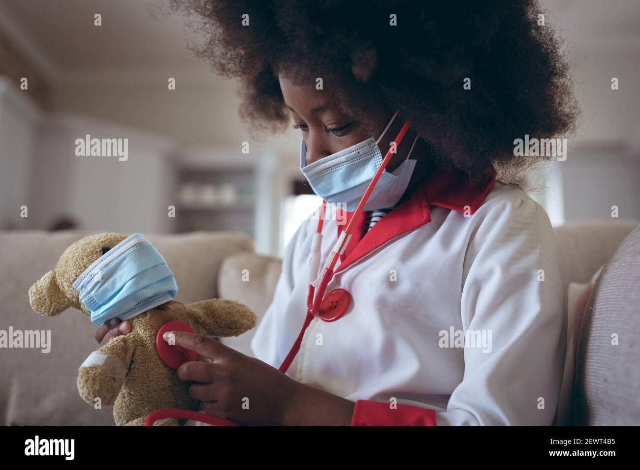 Ragazza afroamericana che gioca medico e paziente con il suo teddy orso Foto Stock