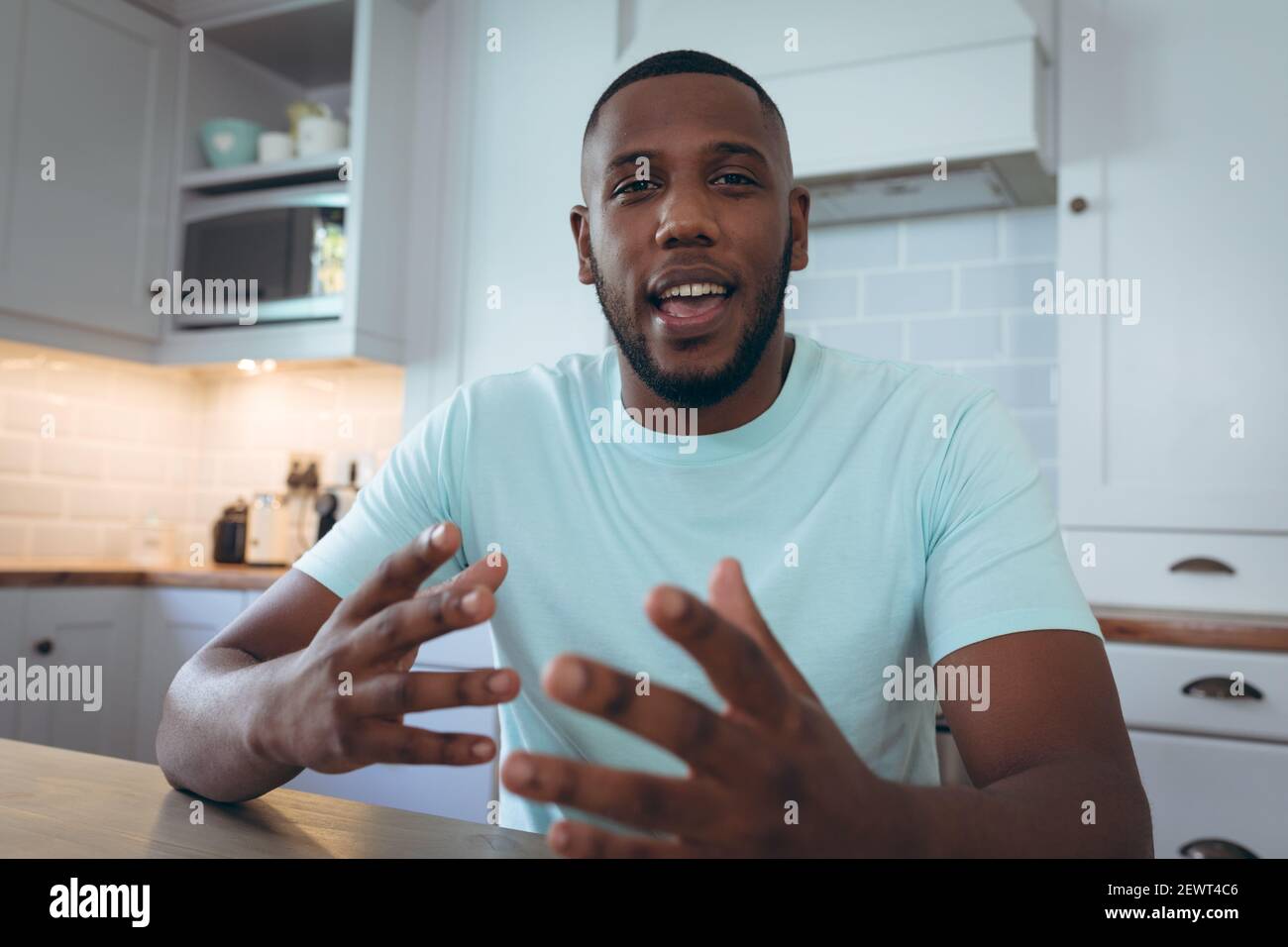 Uomo afro-americano seduto in cucina con una video chat Foto Stock