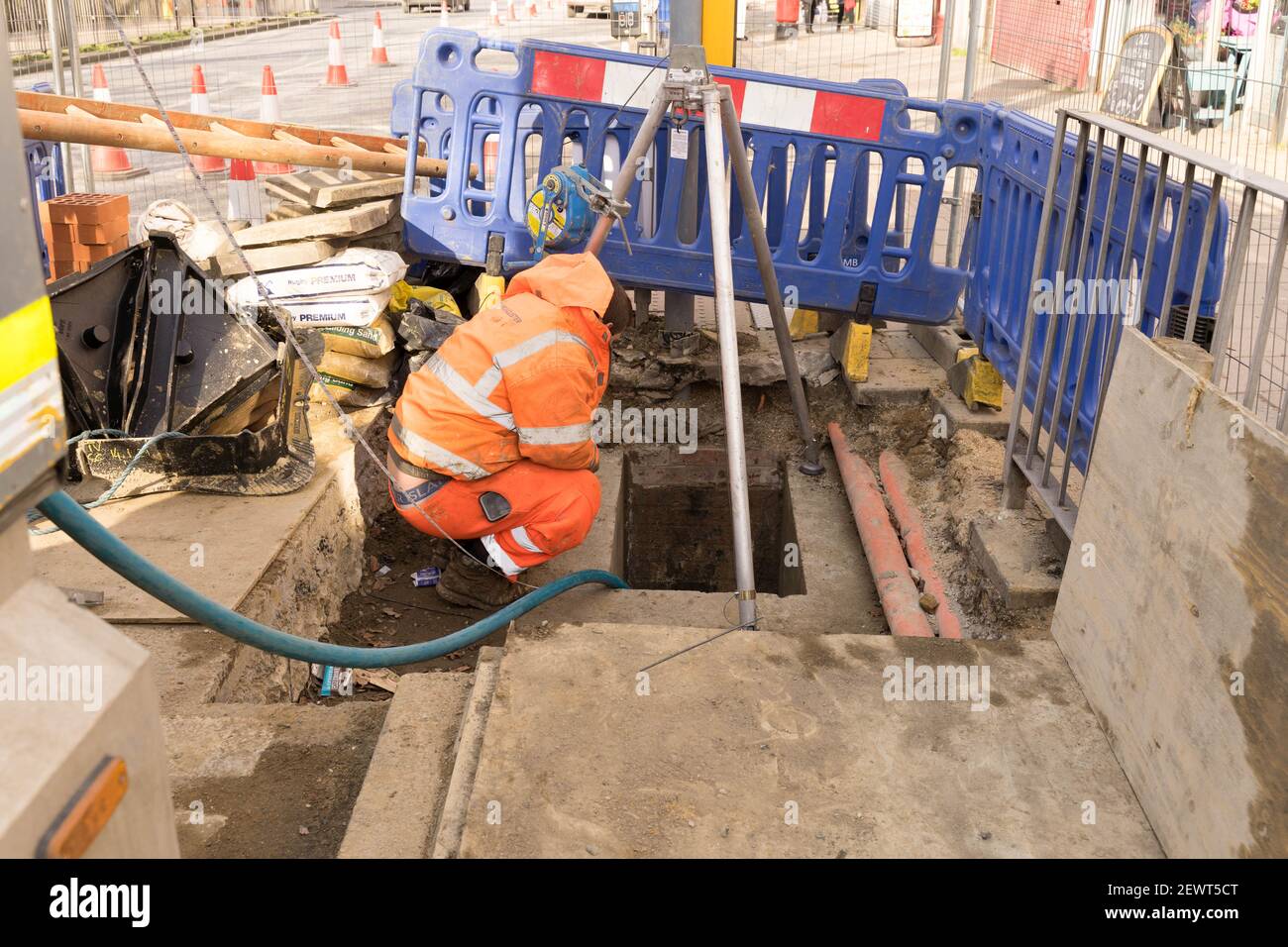 mcallister ingegnere trenchless accovacciato aprendo nel tunnel sotterraneo parlando con il suo collega, cavo verde tirato nel tunnel Foto Stock