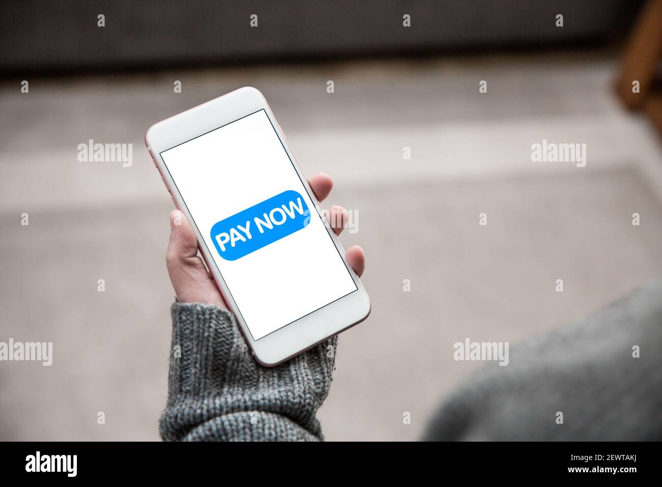 Una ragazza che tiene un telefono cellulare e tocca una paga Ora icona per effettuare una transazione di pagamento per lo shopping online Foto Stock