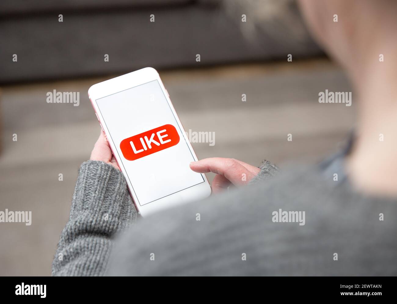 Una donna che tocca un'icona mi piace sul touchscreen di il suo telefono cellulare in un concetto di social media Foto Stock