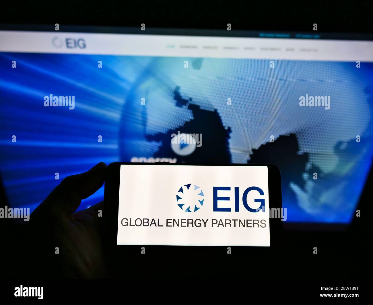 Persona che detiene il telefono cellulare con il logo della società di investimento statunitense EIG Global Energy Partners LLC sullo schermo davanti alla pagina web. Mettere a fuoco il display del telefono. Foto Stock