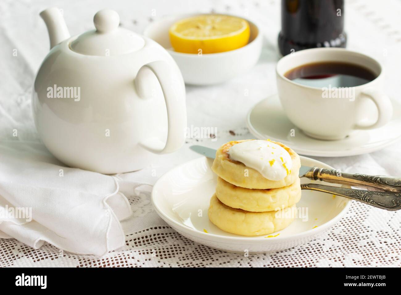 Frittelle al formaggio con panna acida e scorza di limone, servite con tè. Foto Stock