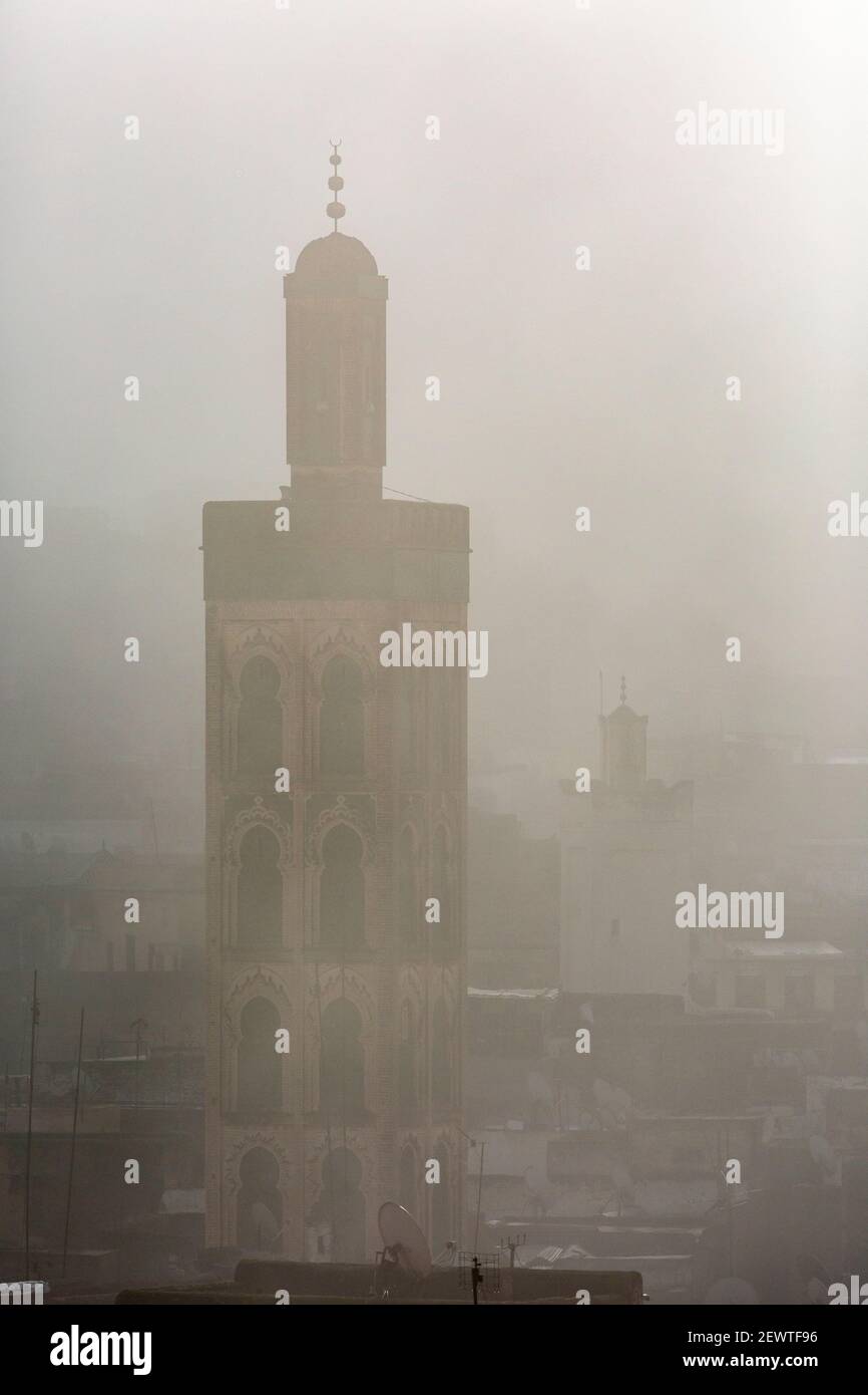 Minareto parzialmente avvolto nella nebbia, come visto da Riad Laayou, Fes, Marocco Foto Stock
