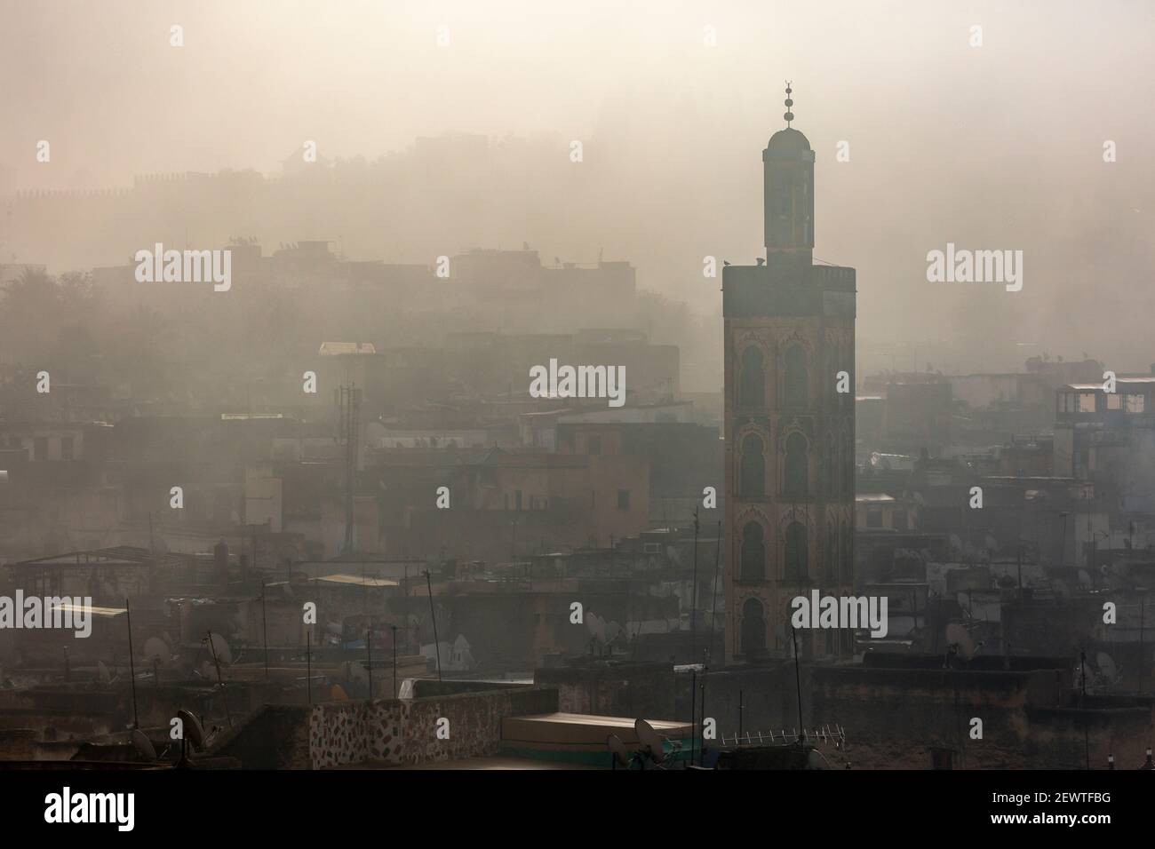 Vista della città della medina di Fes che mostra un minareto durante un'alba nebbia, come visto da Riad Laayoun, Fes, Marocco Foto Stock