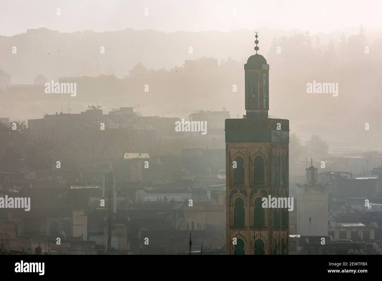 Vista della città della medina di Fes che mostra un minareto durante un'alba nebbia, come visto da Riad Laayoun, Fes, Marocco Foto Stock