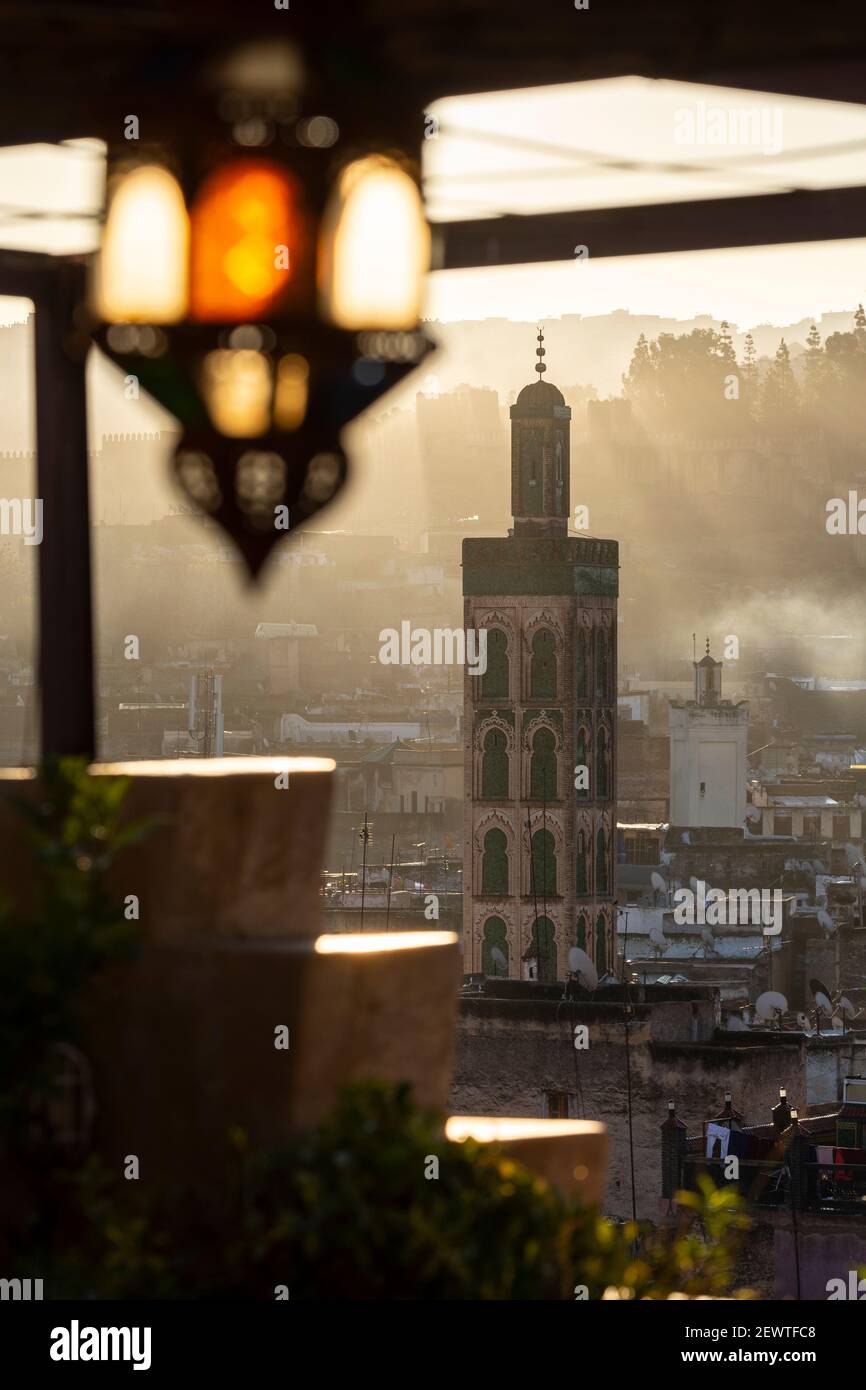 Vista sulla città della medina di Fes che mostra un minareto durante un'alba nebbia, come si vede dalla terrazza sul tetto di Riad Laayoun, Fes, Marocco Foto Stock