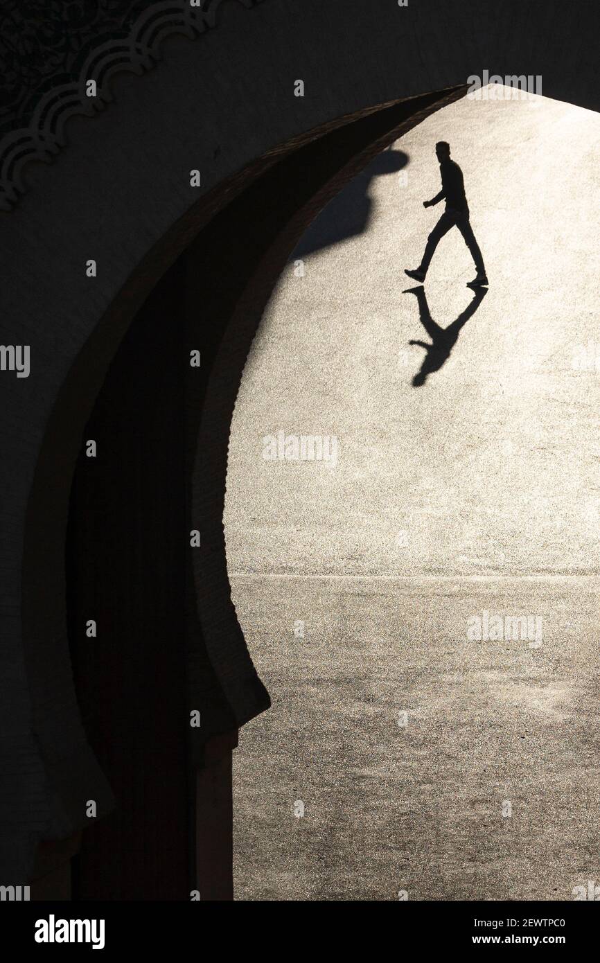 Vista attraverso la porta Blu (Bab Bou Jeloud) che mostra un uomo che cammina e getta una lunga ombra sul terreno, Fes, Marocco Foto Stock