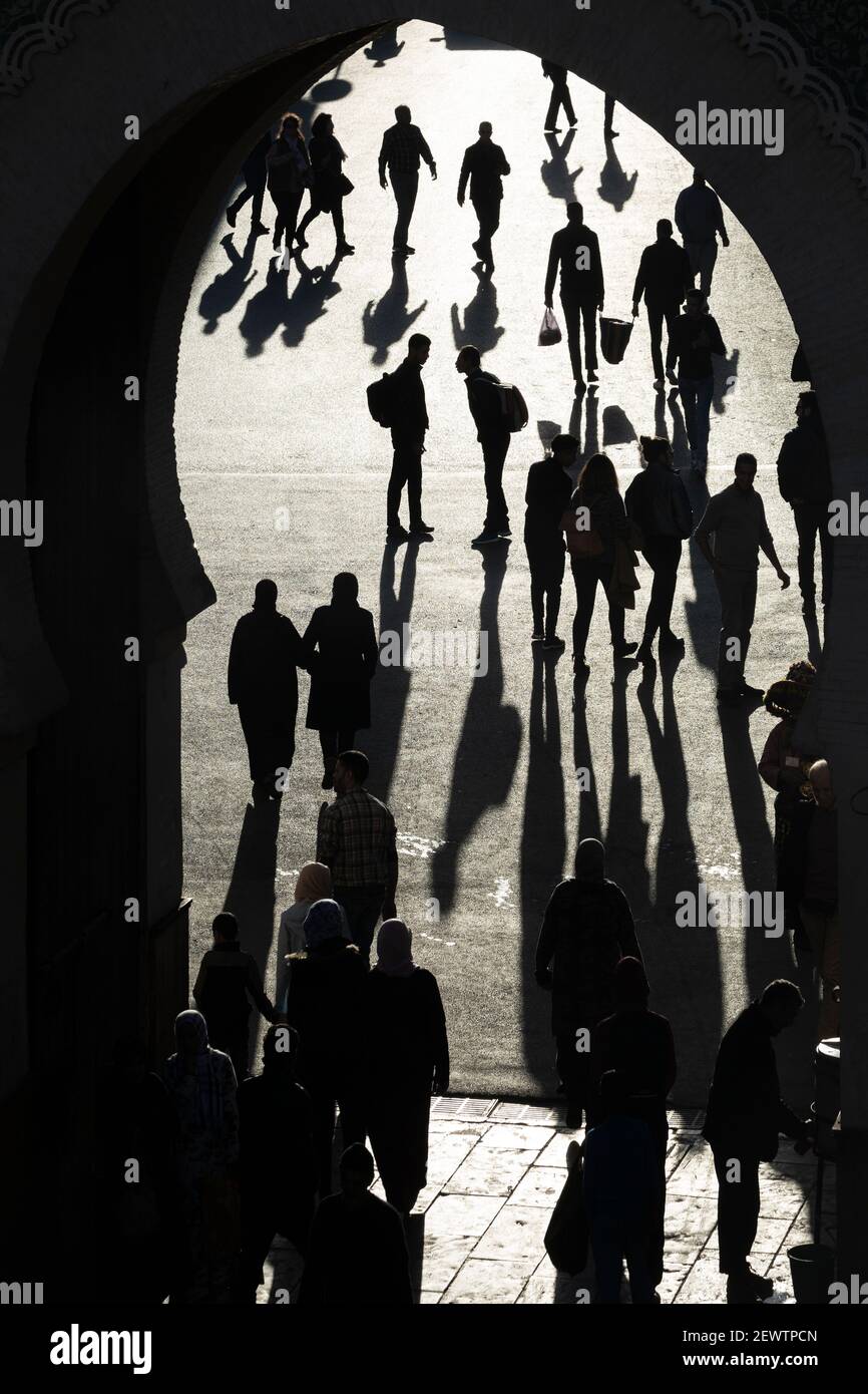 Vista attraverso la porta Blu (Bab Bou Jeloud) che mostra i pedoni che gettano lunghe ombre sul terreno, Fes, Marocco Foto Stock