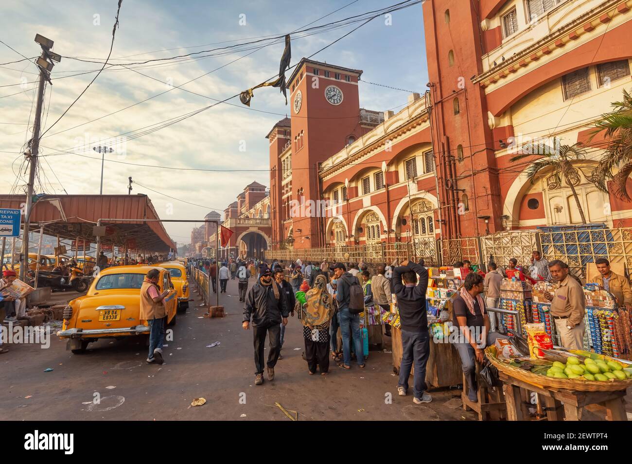 La storica stazione ferroviaria di Howrah con vista sui pendolari, i negozi di strada e la stazione dei taxi a Kolkata, India Foto Stock