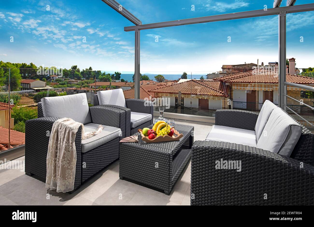 Panorama di concetto di ricreazione del patio moderno con mobili in rattan grigio vimini. Poltrone contemporanee, divano, tavolo sulla terrazza sul tetto di mare di lusso Foto Stock
