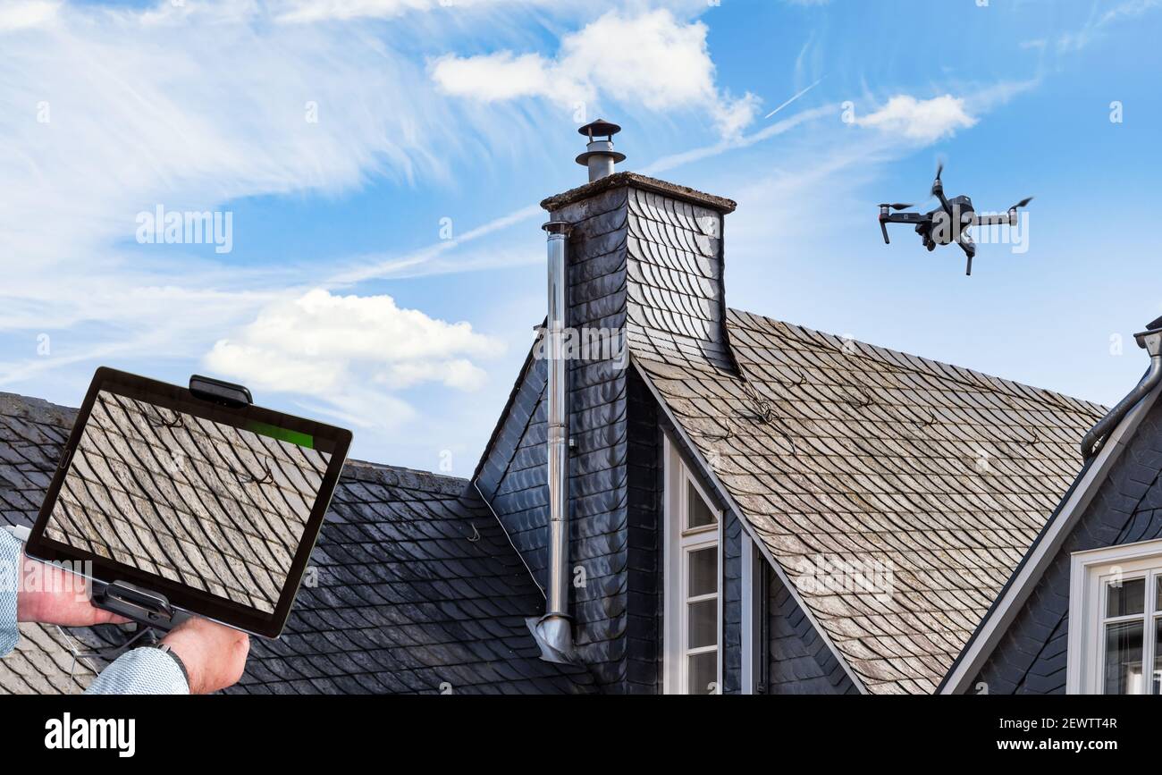 Drone in aria ispezionando il tetto sopra la casa. Primo piano del drone e del tetto. Foto Stock