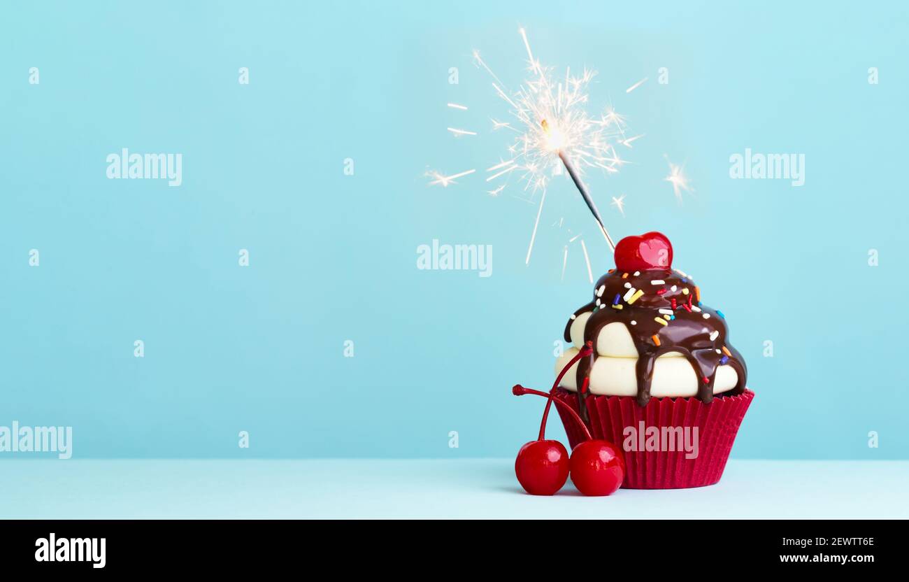 Cupcake di celebrazione con ciliegia e scintilla Foto Stock