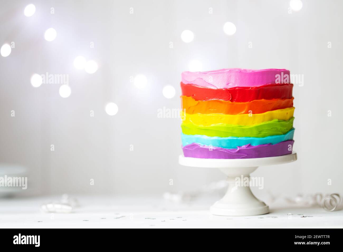 Torta arcobaleno colorata su un cakestand Foto Stock