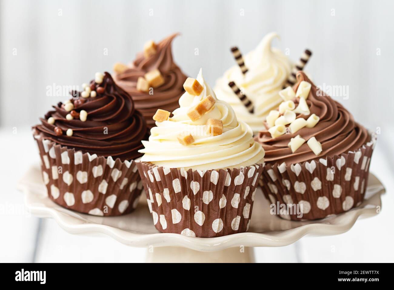 Varietà di cupcake al cioccolato decorate con crema di burro e pezzi di fudge Foto Stock