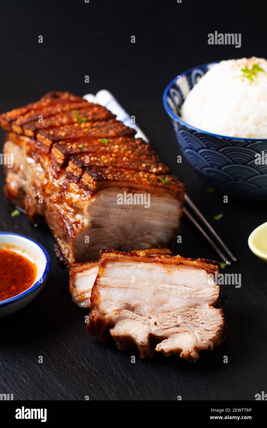 Il concetto di cibo focalizza la pancia di maiale croccante cotta in casa asse di pietra ardesia nero con spazio di copia Foto Stock